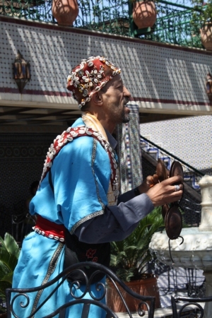 A Gnawa musician in a traditional outfit with beadwork, cowry shells, embroidery and tassels.