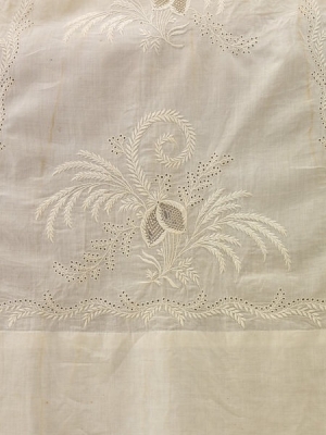 Detail of floral motif worked in Ayrshire whitewwork with central &lsquo;lace&rsquo; insets surrounded by satin stitch flowers, stems, leaves, and small eyelets (c. 1825, Scotland)