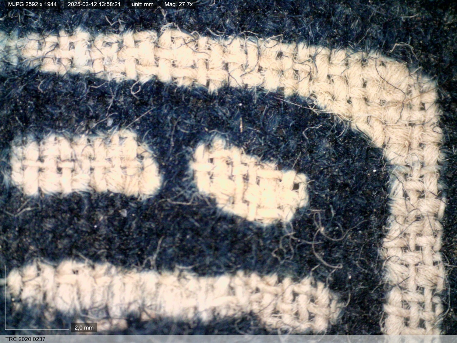 Fragment of TRC 2020.0237. Dino-Lite, magnification 27.7x.The photograph shows details of the spin direction and weave structure, as well as the effect of the resist-dyeing.