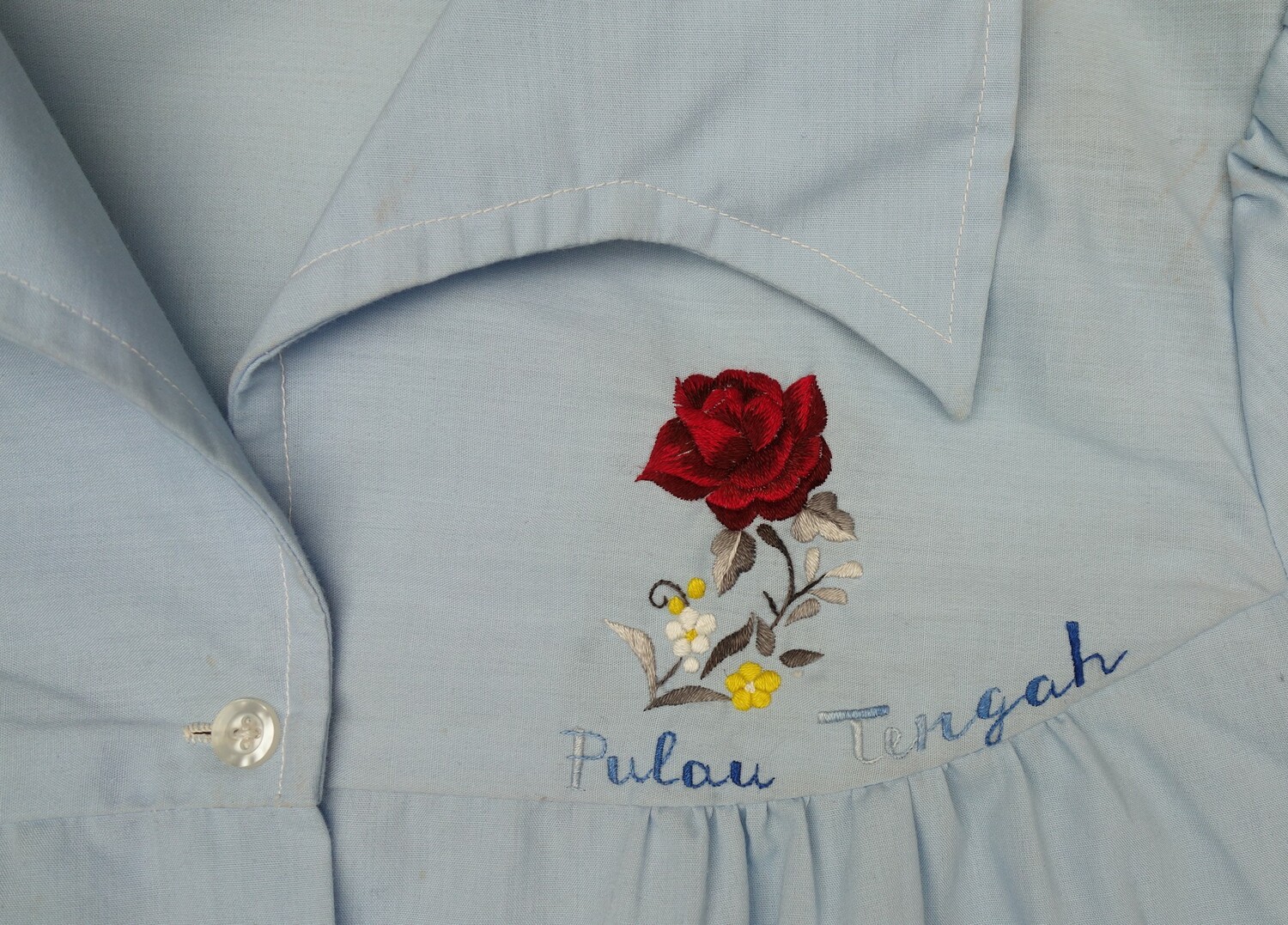 Detail of a child's blouse distributed among Vietnamese boat people that fled their country after 1975. The embroidery gives the name of the refugee camp on the Malaysian island of Pulau Tengah (TRC 2021.0417 2