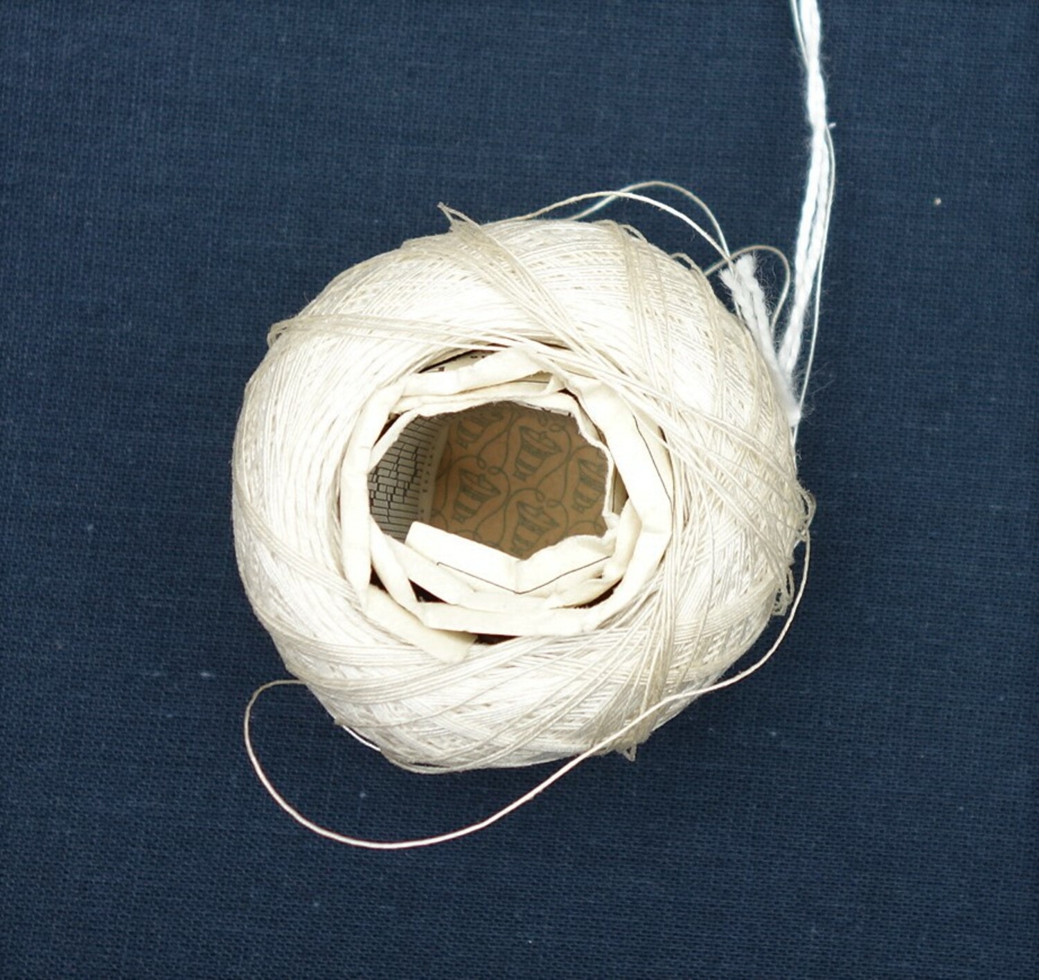 Ball of white linen thread, DMV, France, with rolled-up pattern sheet tucked inside (TRC 2021.0775h).