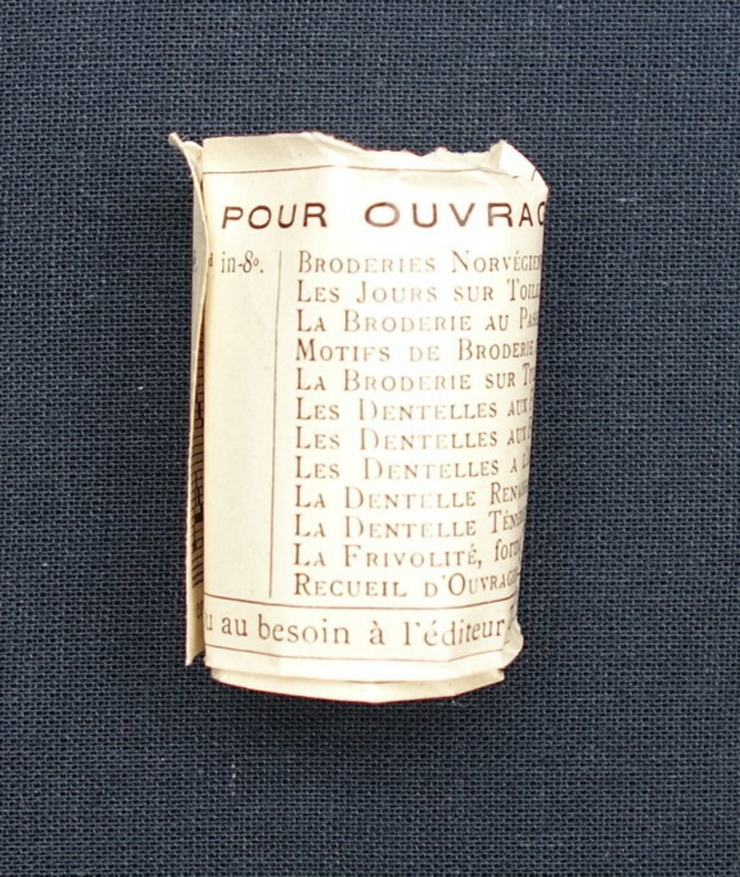 Rolled-up pattern sheet from inside a ball of thread, DMC, France (TRC 2021.0775i).