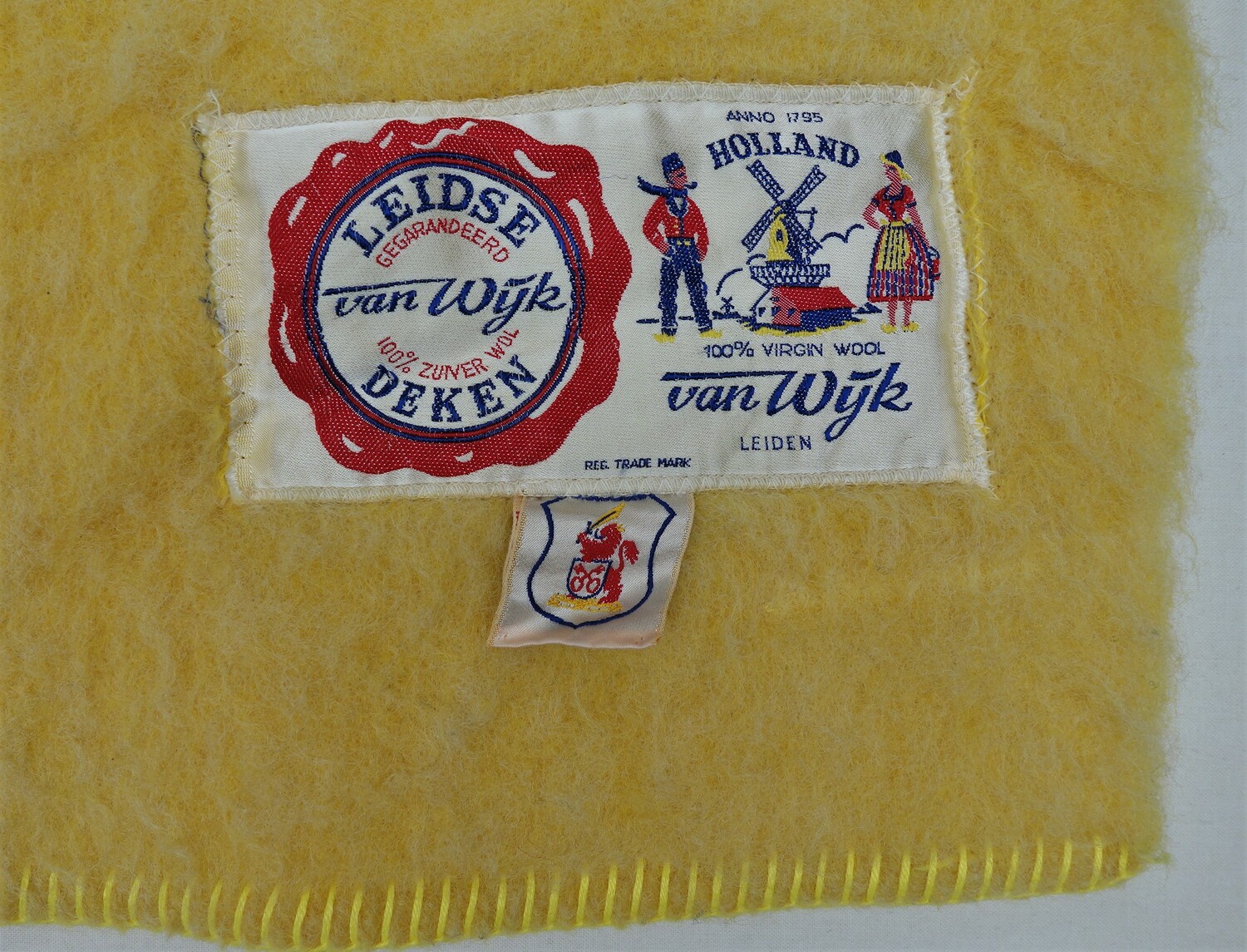 Label of a Leiden 'Van Wijk' blanket (TRC 2021.1344). The label says: "Anno 1795 HOLLAND 100% VIRGIN WOOL &nbsp;van Wijk &nbsp;Leiden &nbsp;&nbsp;LEIDSE GEGARANDEERD VAN WIJK 100% &nbsp;ZUIVER WOL DEKEN"