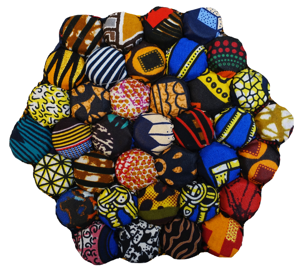 Multi-coloured mat from Namibia, 2024, made out of metal bottle caps. Each cap is covered with different, wax-printed fabrics individually cut out and then hand sewn together in an octogonal shape (TRC 2024.3444).