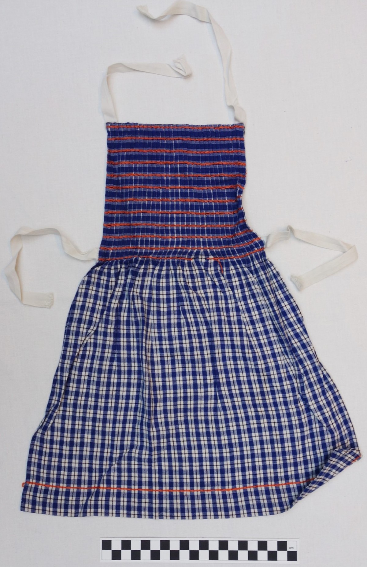 Girl's apron in orange, white and blue, early 1940s (TRC 2010.0569).
