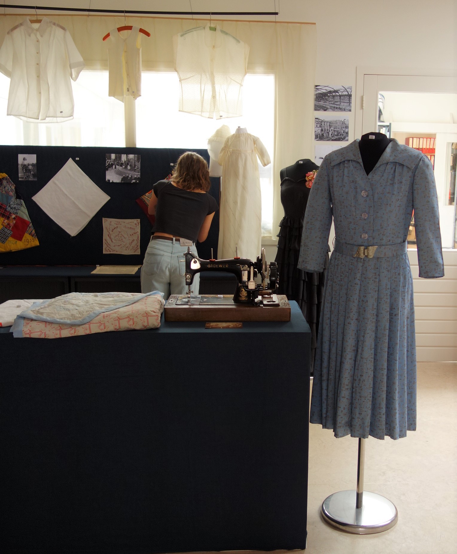 Volunteers at the TRC setting up the exhibition; in the window are nylon blouses and gowns made from parachute silk. The sewing machine was used by a Leiden family to make garments, during the Occupation.